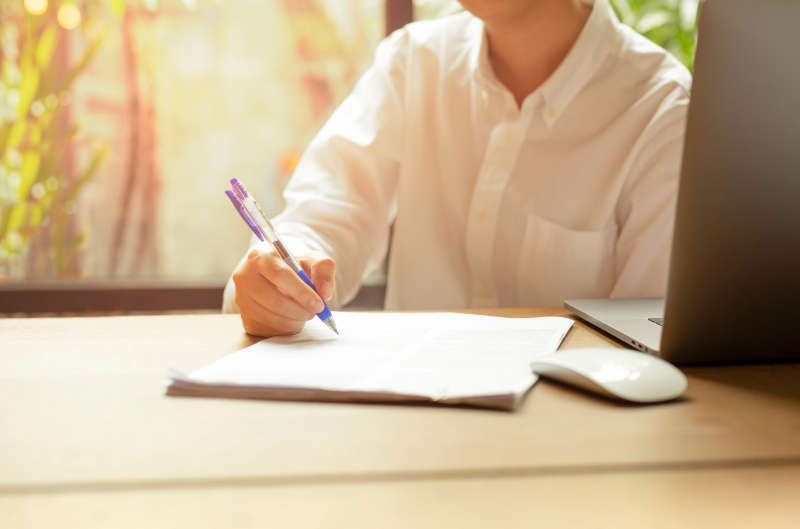 Hand Filling Document Form Contract With Laptop An Mouse On Wood